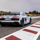 2023 audi r8 gt in grey parked on a race track, seen from the rear, with red and white striped curbing on either side of the car and a dusky sky in the background